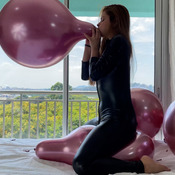 Catsuit girl siting on metal balloons