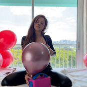 Catsuit girl siting on metal balloons