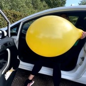 Blow to pop a big yellow balloon out of the car